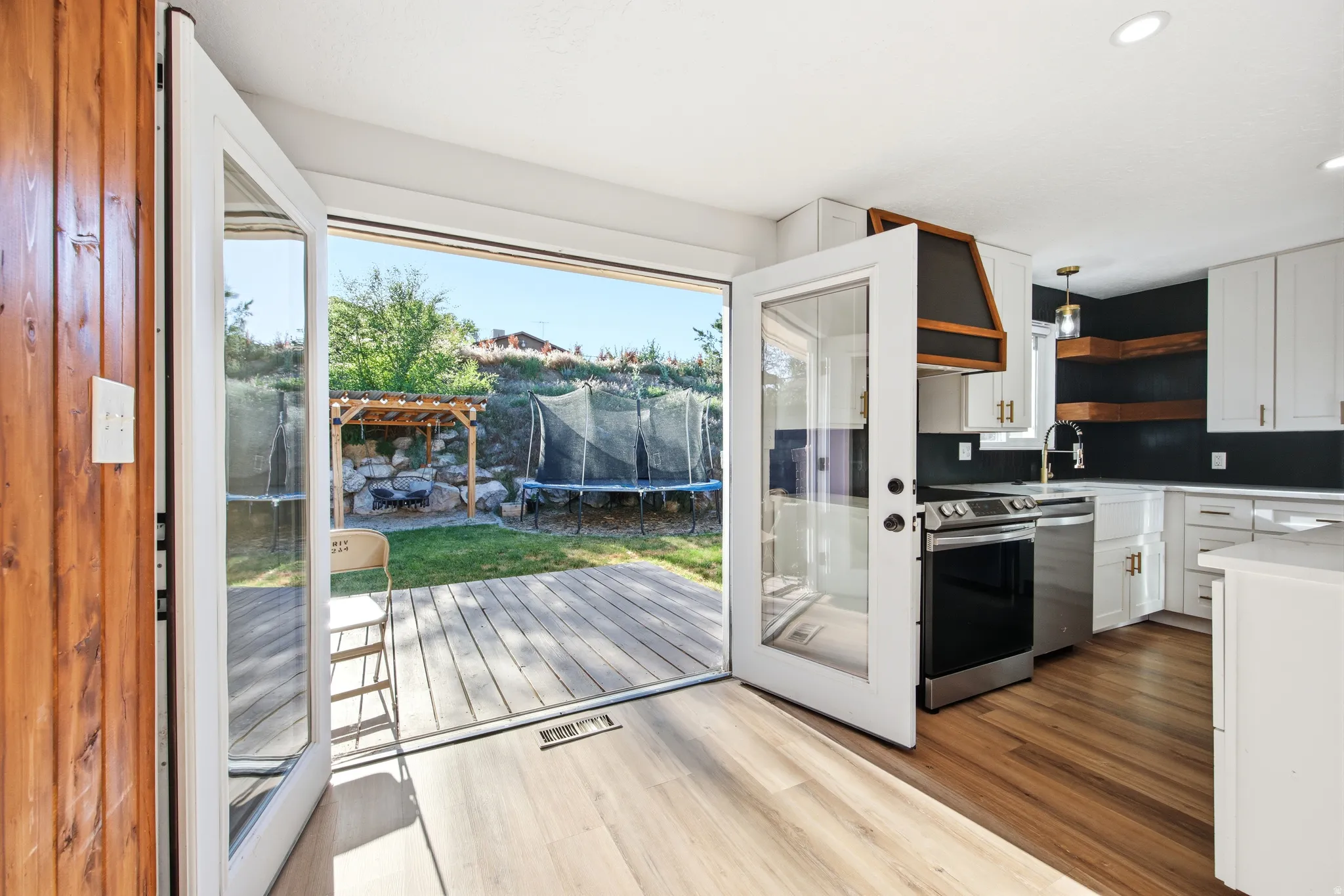 Kitchen featuring wood-finish flooring, white cabinetry, and stainless steel appliances
