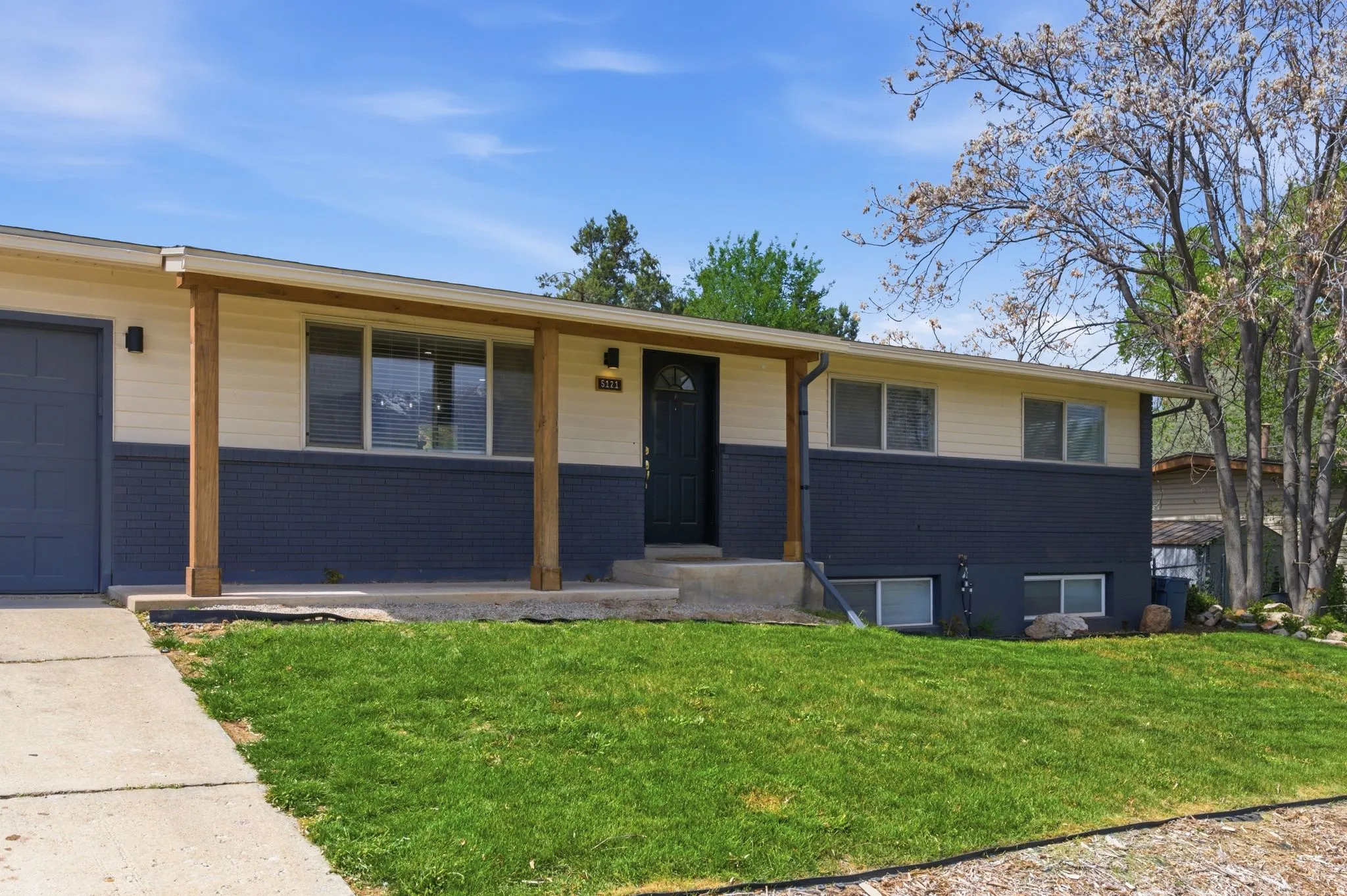 Single story home featuring a front lawn, covered porch, and an attached garage