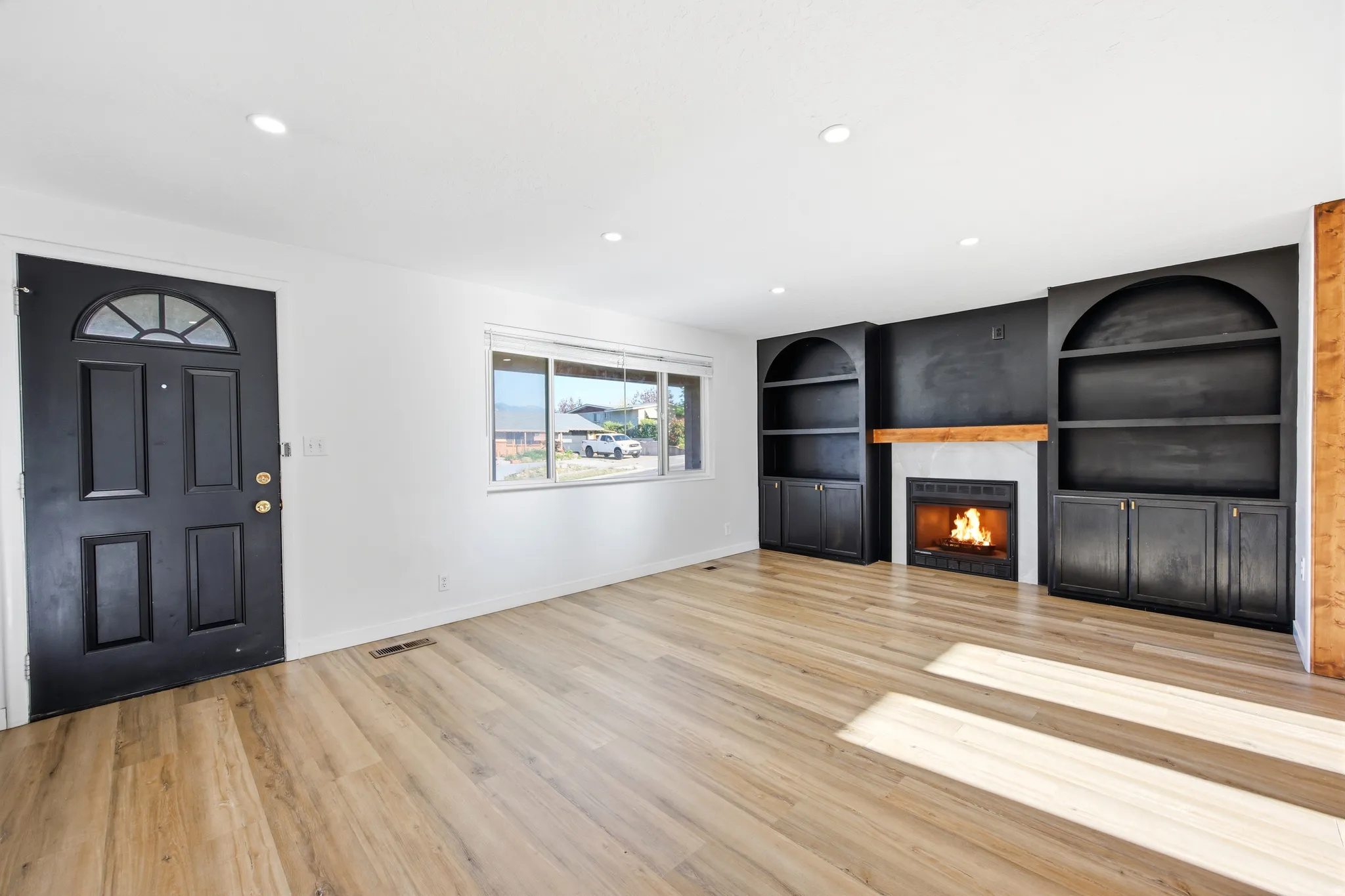Living area featuring wood-finish flooring, recessed lighting, and a prominent fireplace with a light-toned mantel