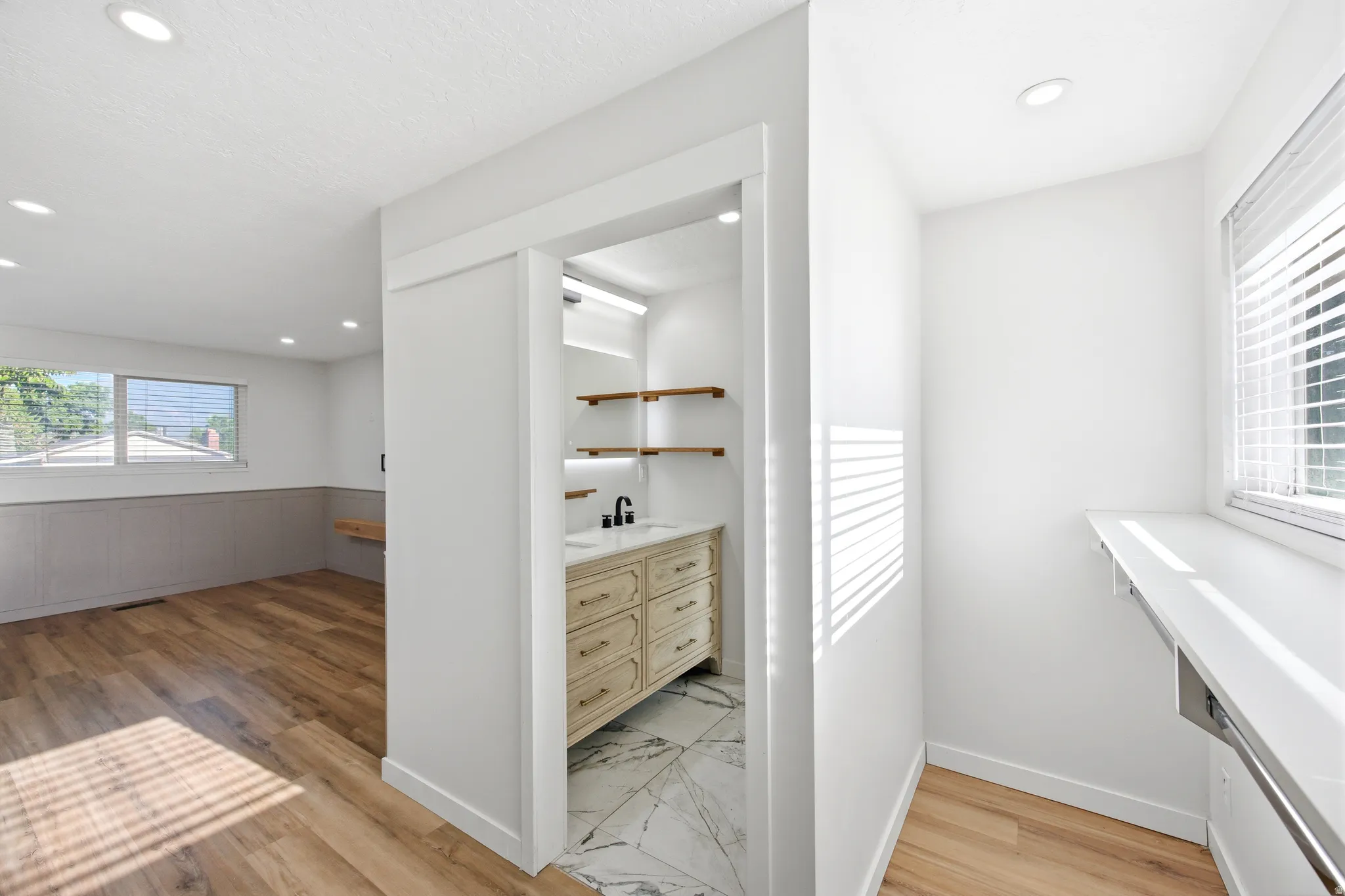 Contemporary vanity space featuring a light wood-finish vanity with drawer storage, a black faucet, and a vessel sink