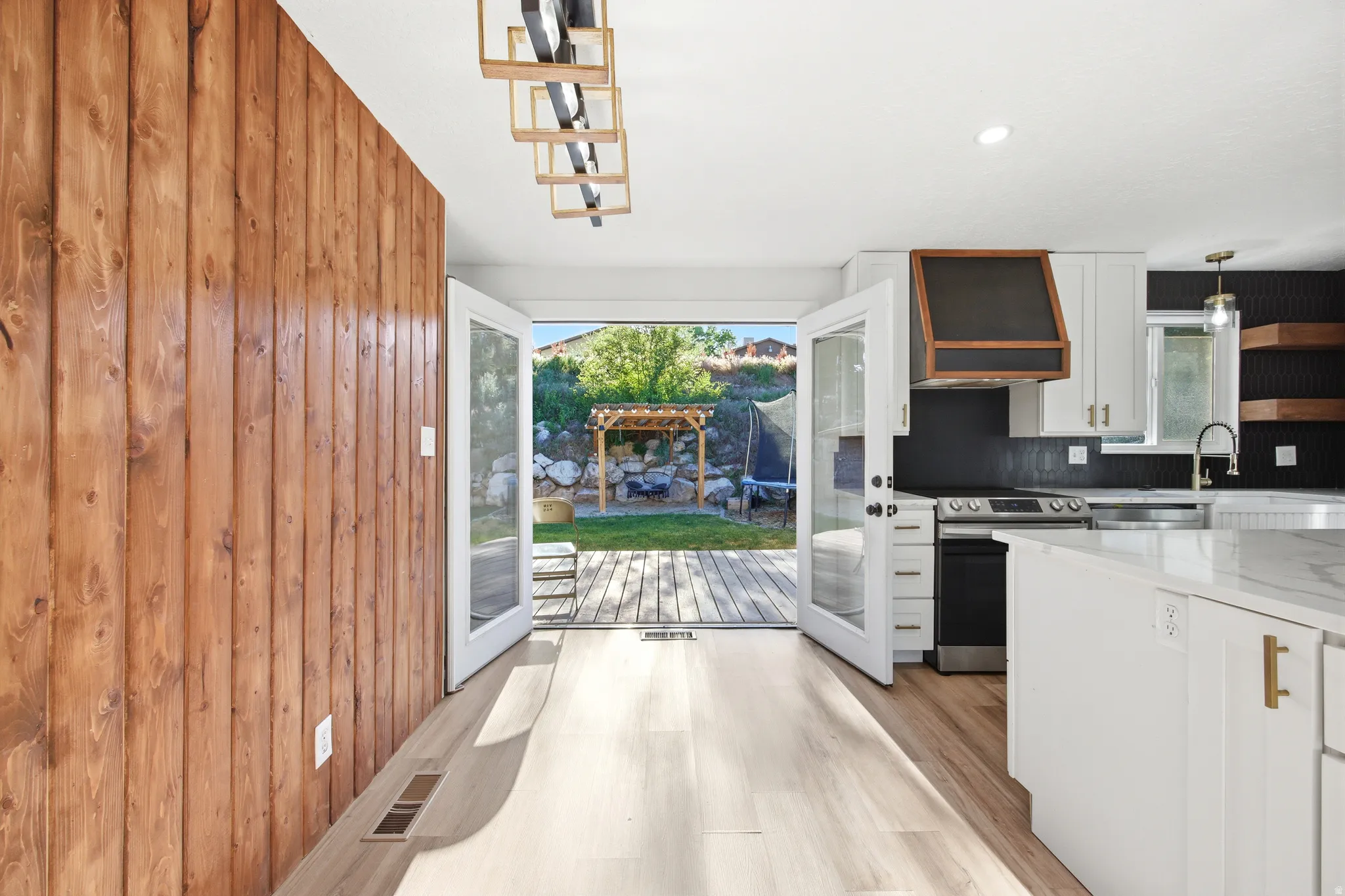 Kitchen featuring white cabinetry, a large island with a light-toned countertop, and a dark tile backsplash