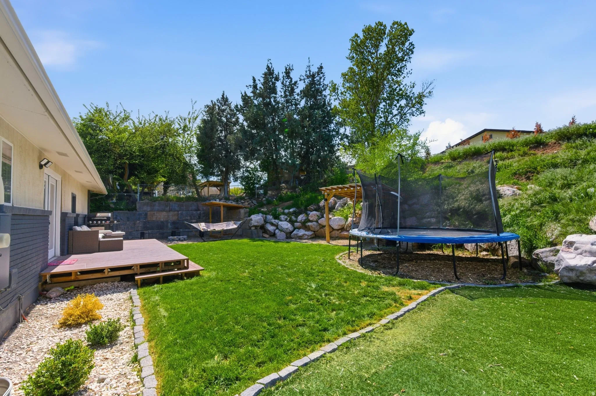 View of yard with a trampoline and a deck