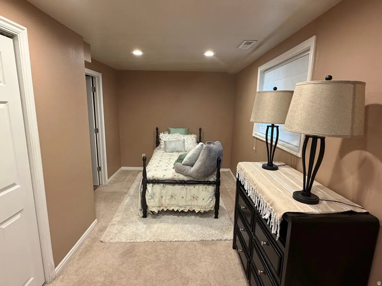 Living area with light carpet and recessed lighting