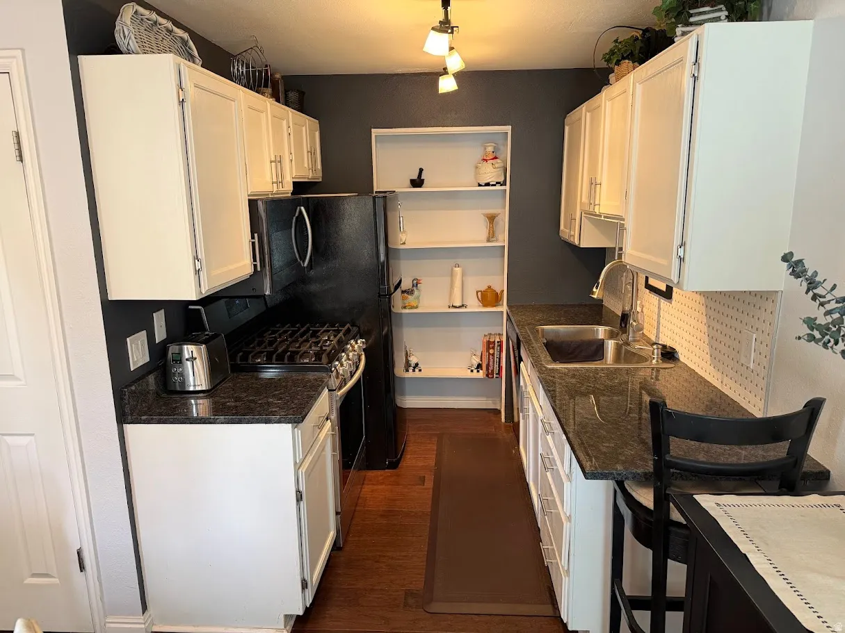 Kitchen with white cabinetry, gas range, decorative backsplash, dark stone countertops, and dark wood-style floors