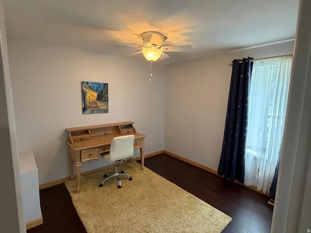 Home office with dark wood finished floors and ceiling fan