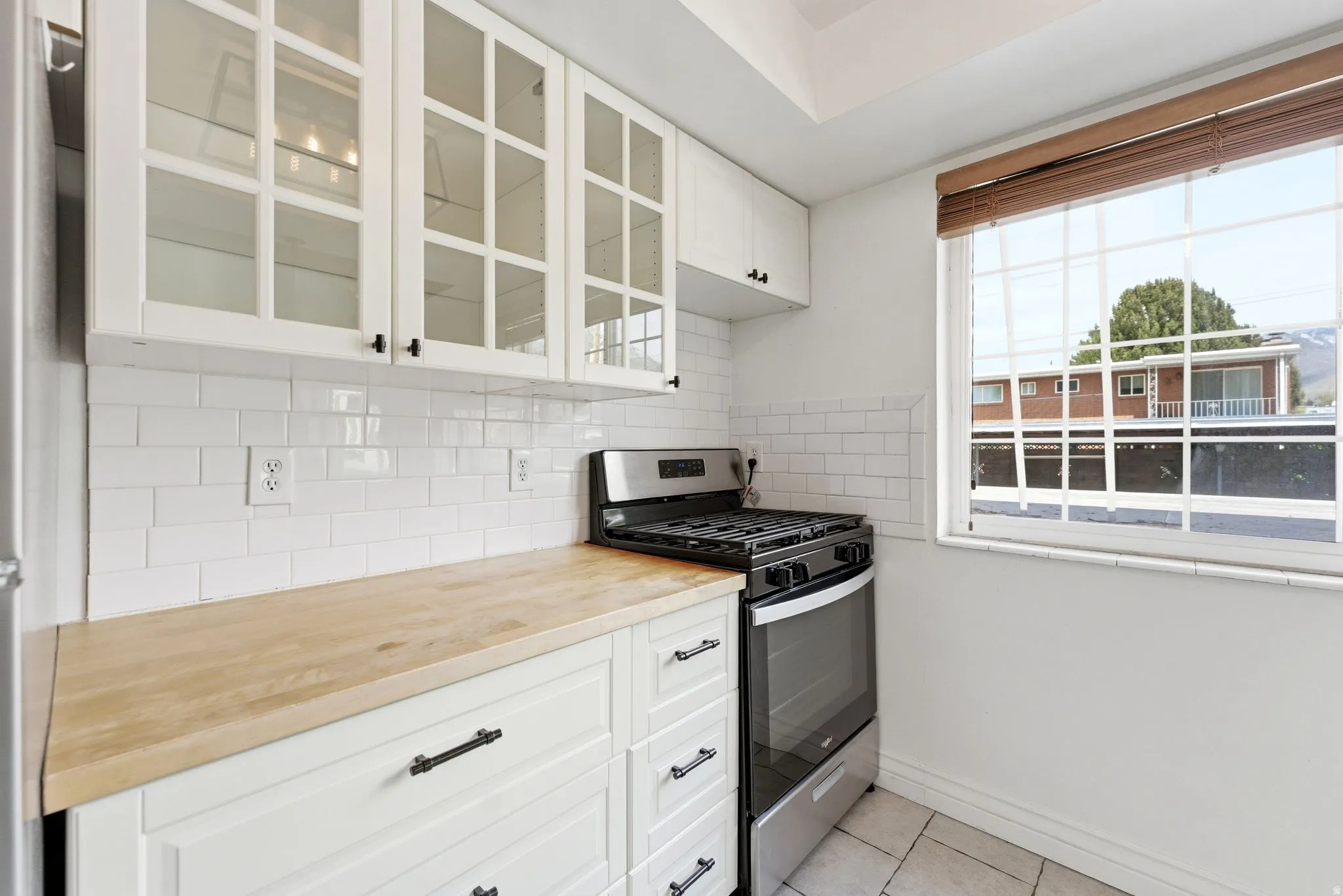 Kitchen featuring white cabinetry, stainless steel range with gas cooktop, and glass fronted cabinets