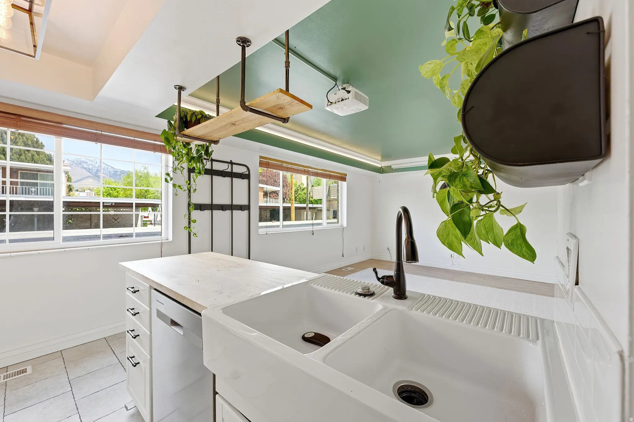 Kitchen with white cabinets, dishwasher, light countertops, light tile patterned flooring, and a mountain view