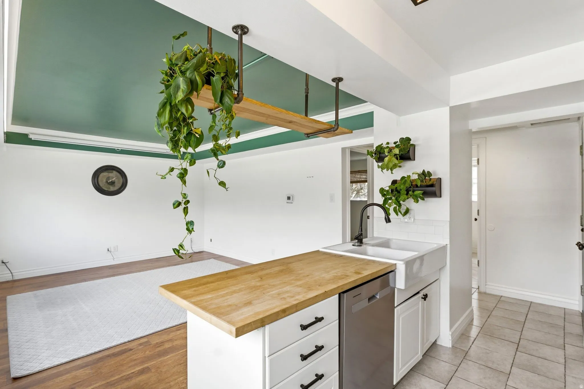 Kitchen with butcher block countertops, stainless steel dishwasher, open floor plan, a peninsula, and white cabinets