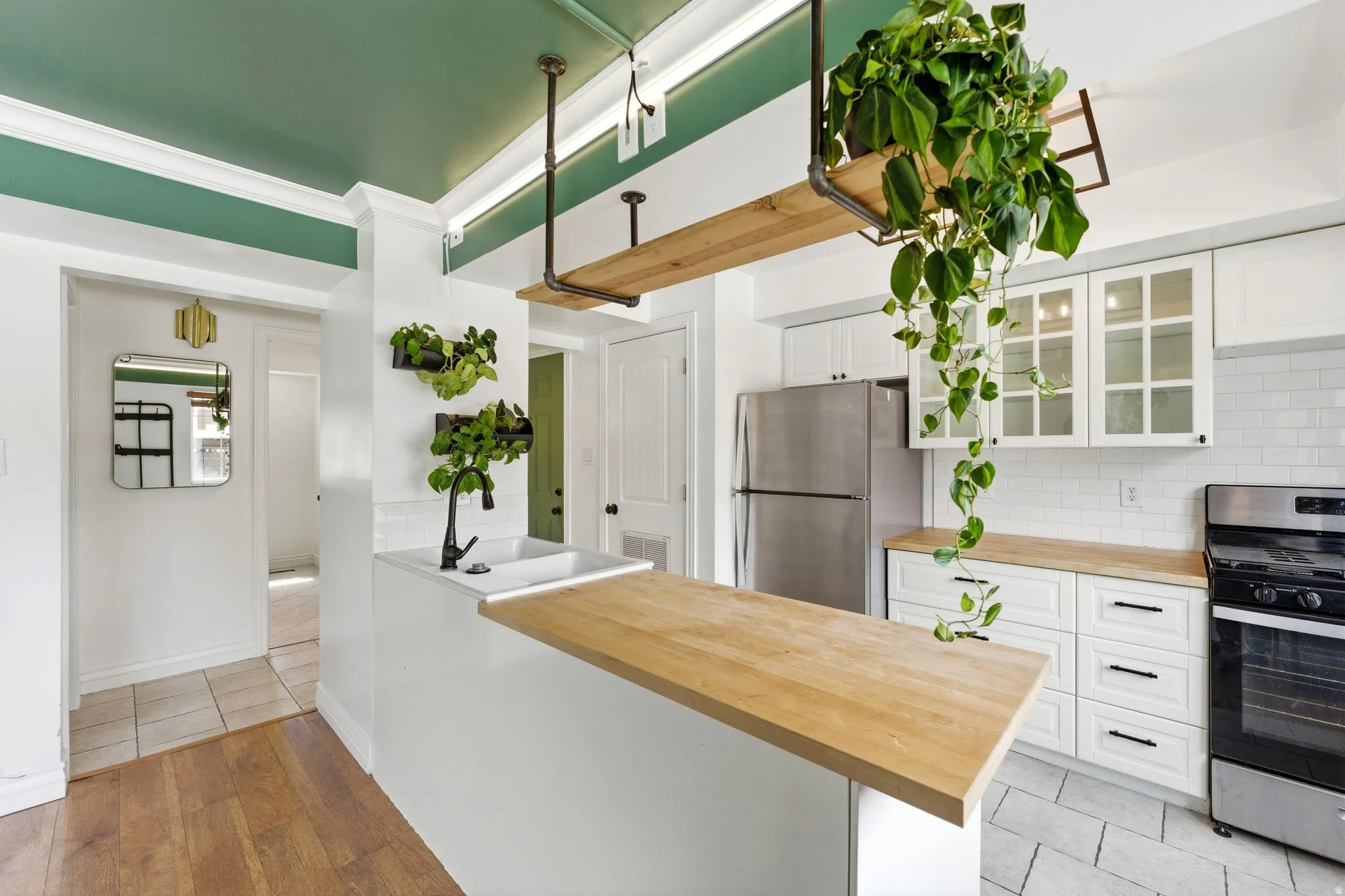 Kitchen featuring white cabinets, glass fronted cabinets, stainless steel appliances, wooden counters, and backsplash