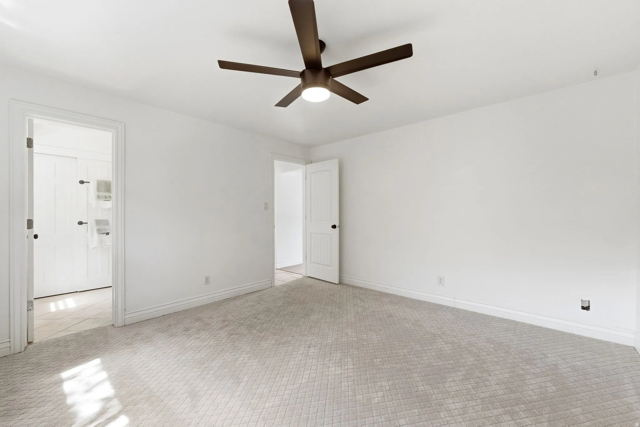 Unfurnished bedroom featuring a ceiling fan and light carpet