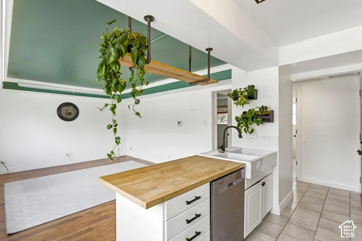 Kitchen with butcher block countertops, stainless steel dishwasher, open floor plan, a peninsula, and white cabinets