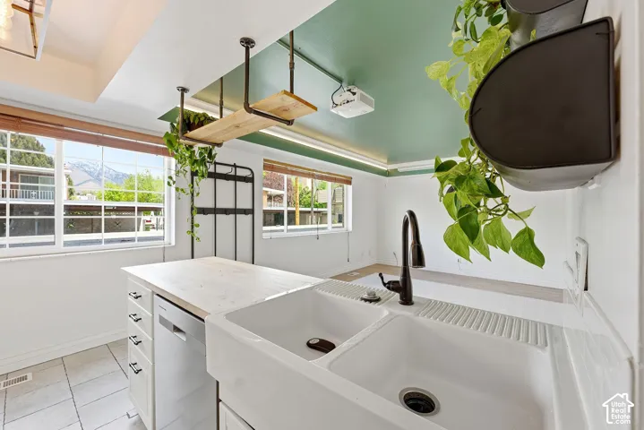 Kitchen with white cabinets, dishwasher, light countertops, light tile patterned flooring, and a mountain view