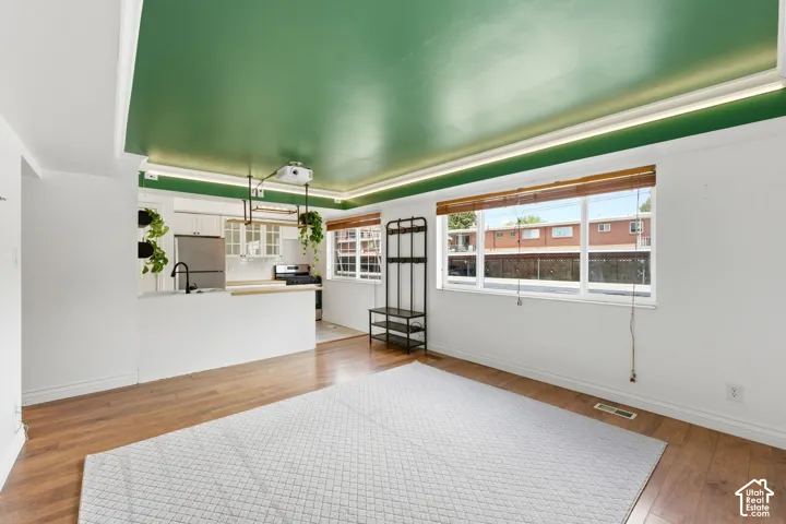 Living area with light wood-type flooring and a tray ceiling