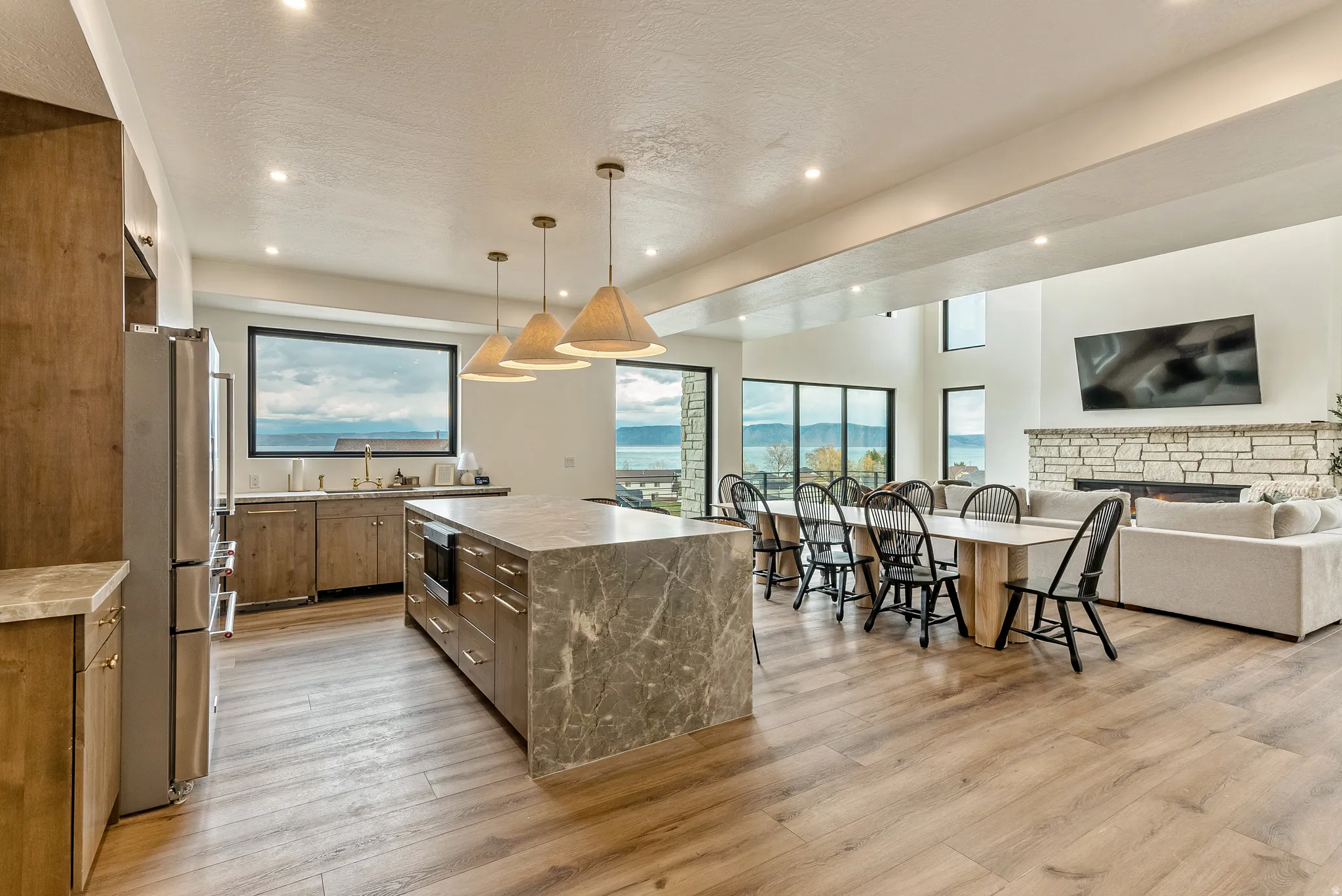 Kitchen with open floor plan, a spacious island, stainless steel appliances, decorative light fixtures, and light wood-style flooring