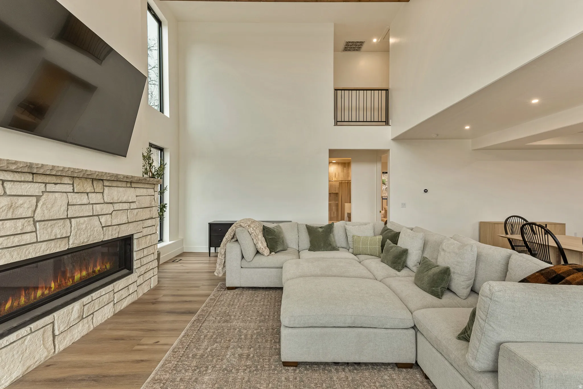 Living area featuring wood finished floors, a high ceiling, a stone fireplace, and recessed lighting