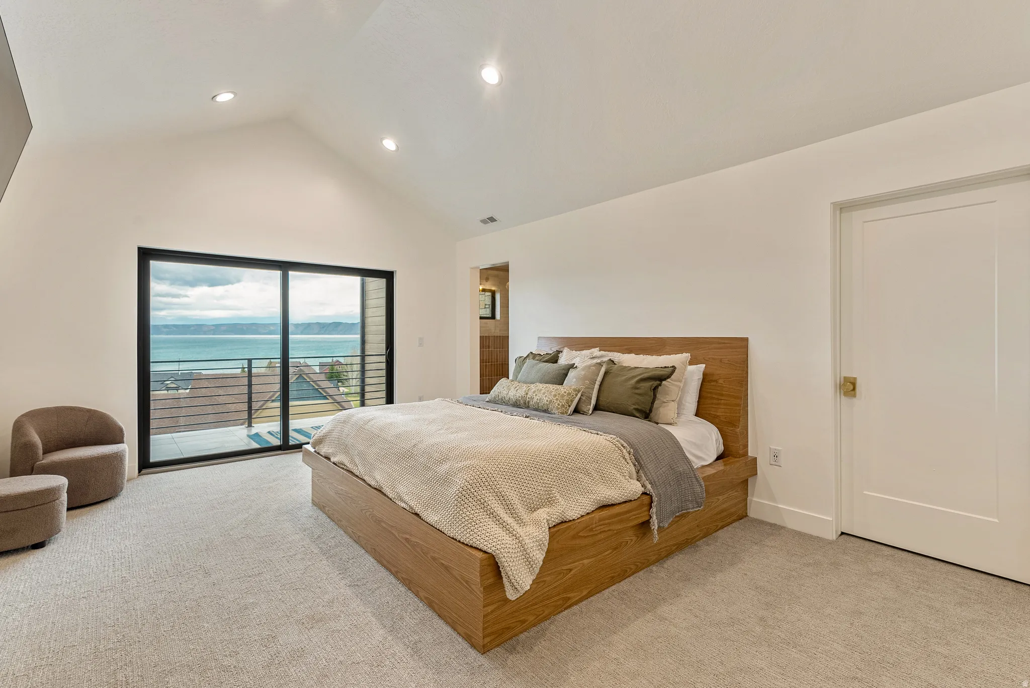 Bedroom with light carpet, access to outside, recessed lighting, a water view, and a high ceiling