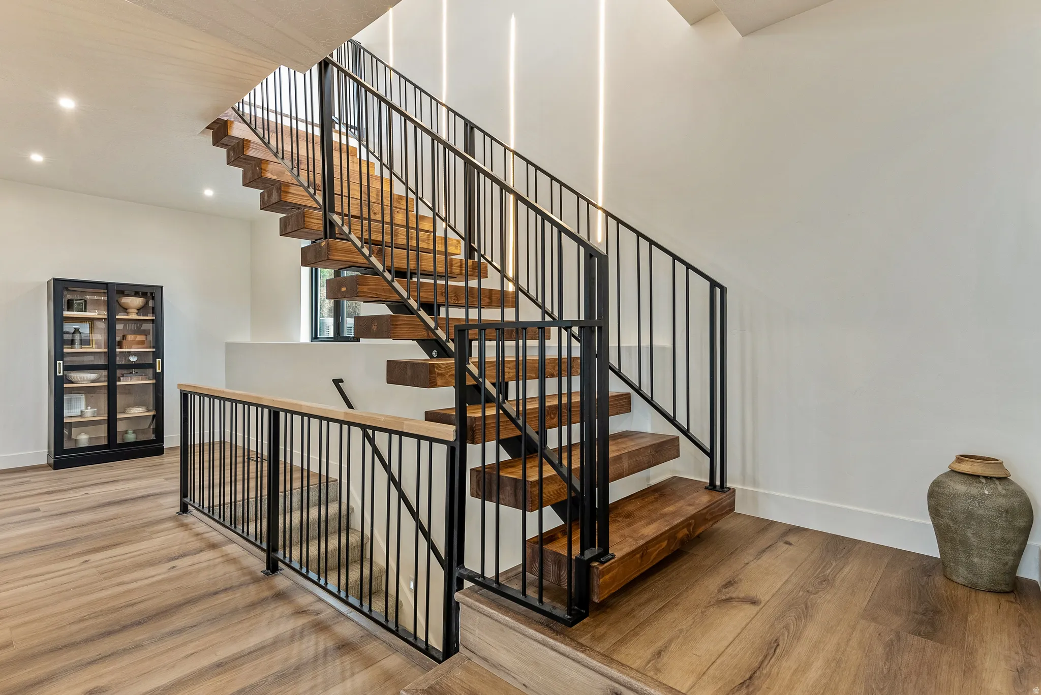 Staircase with wood finished floors and recessed lighting
