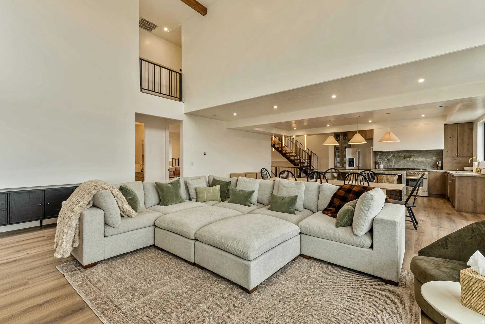 Living room with light wood-style floors, recessed lighting, and a high ceiling