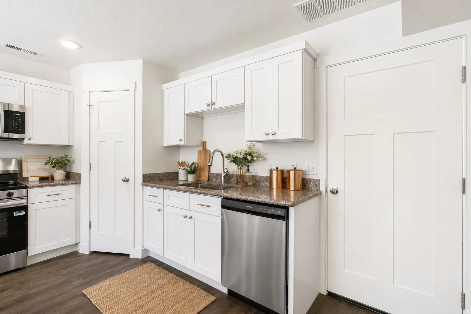 Kitchen with white cabinets, dark stone counters, stainless steel appliances, and dark wood-style floors