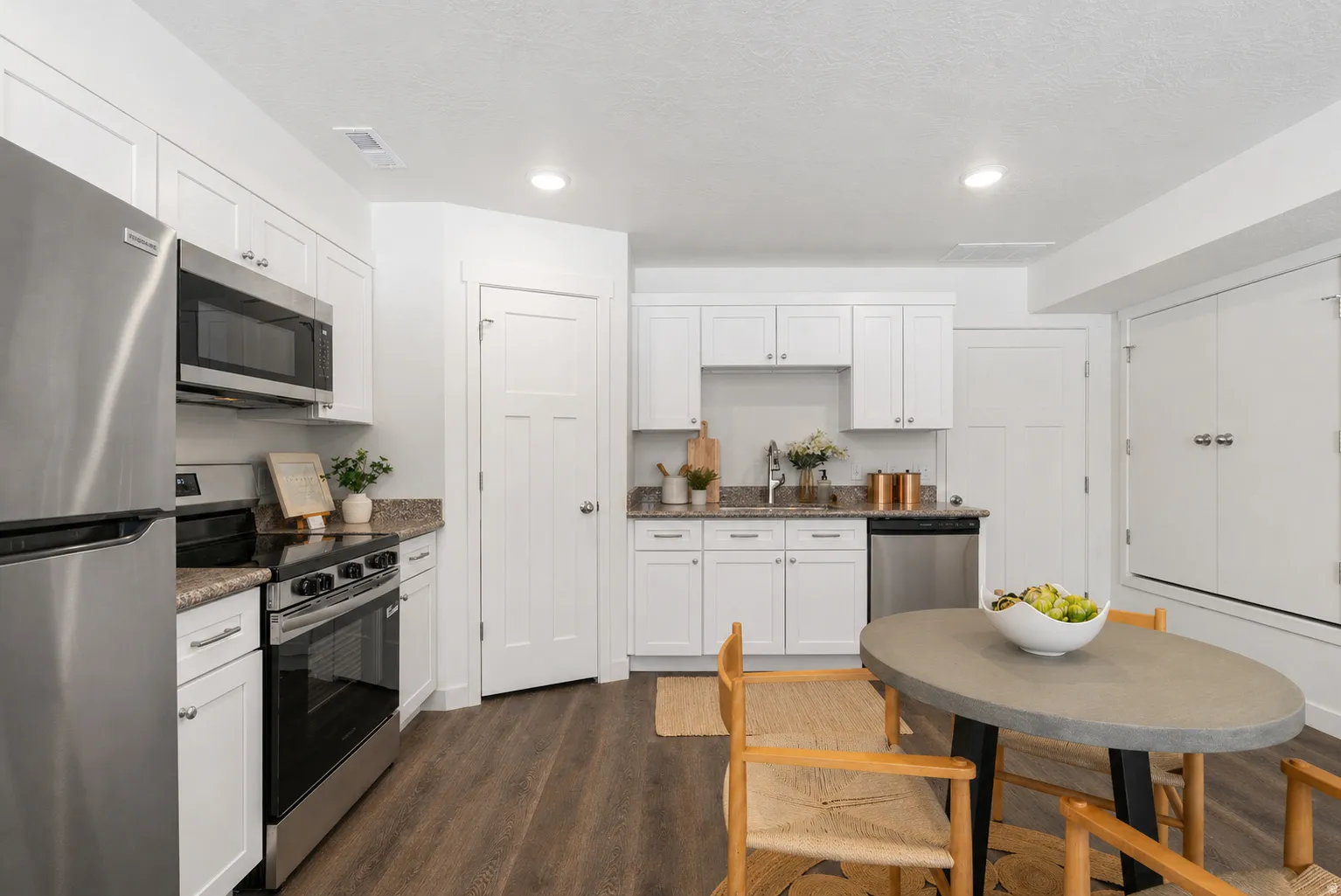 Kitchen with stainless steel appliances, dark wood finished floors, white cabinets, and recessed lighting