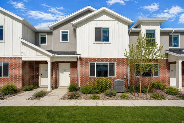 View of front of house with board and batten siding, brick siding, a front yard, and a porch