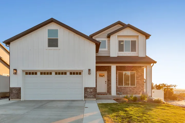 View of front facade featuring a porch, driveway, board and batten siding, and stone siding