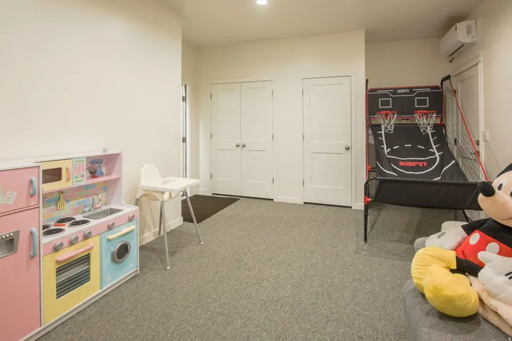 Playroom with a wall mounted mini split and dark colored carpet