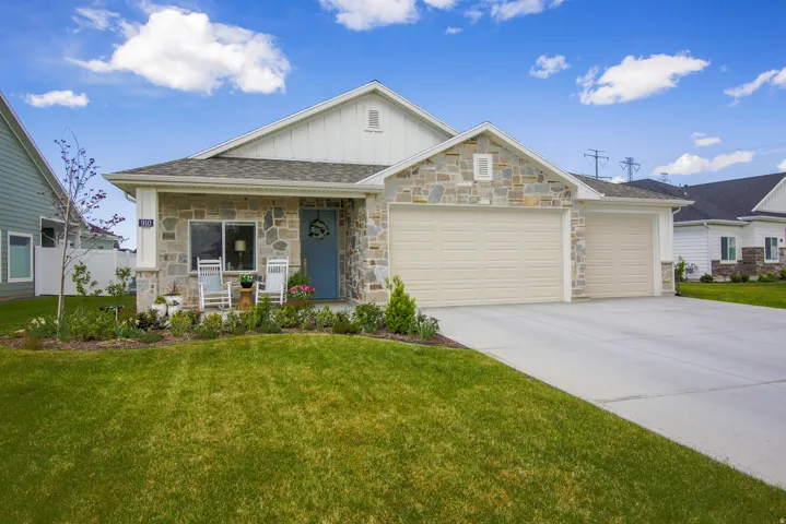 View of front of home featuring board and batten siding, a porch, an attached garage, a front yard, and concrete driveway