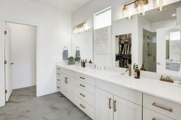 Full bathroom featuring double vanity, a spacious closet, light marble finish floors, and a marble finish shower