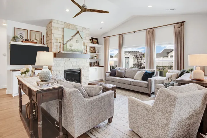 Living area featuring ceiling fan, a stone fireplace, light wood-style flooring, recessed lighting, and built in features
