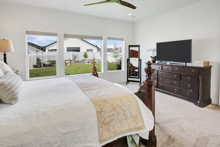 Bedroom with light colored carpet and a ceiling fan