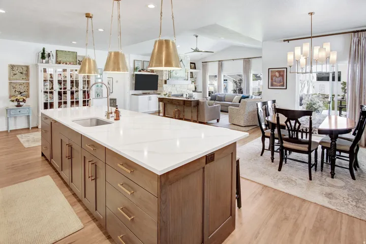 Kitchen featuring wood finish cabinetry, ceiling fan, light wood-type flooring, an island with sink, and hanging lights