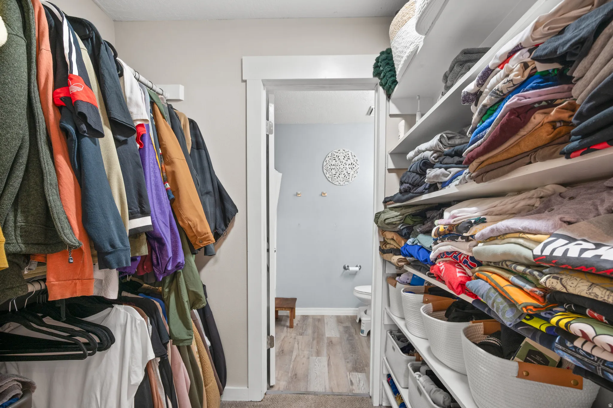 Walk in closet with light wood finished floors