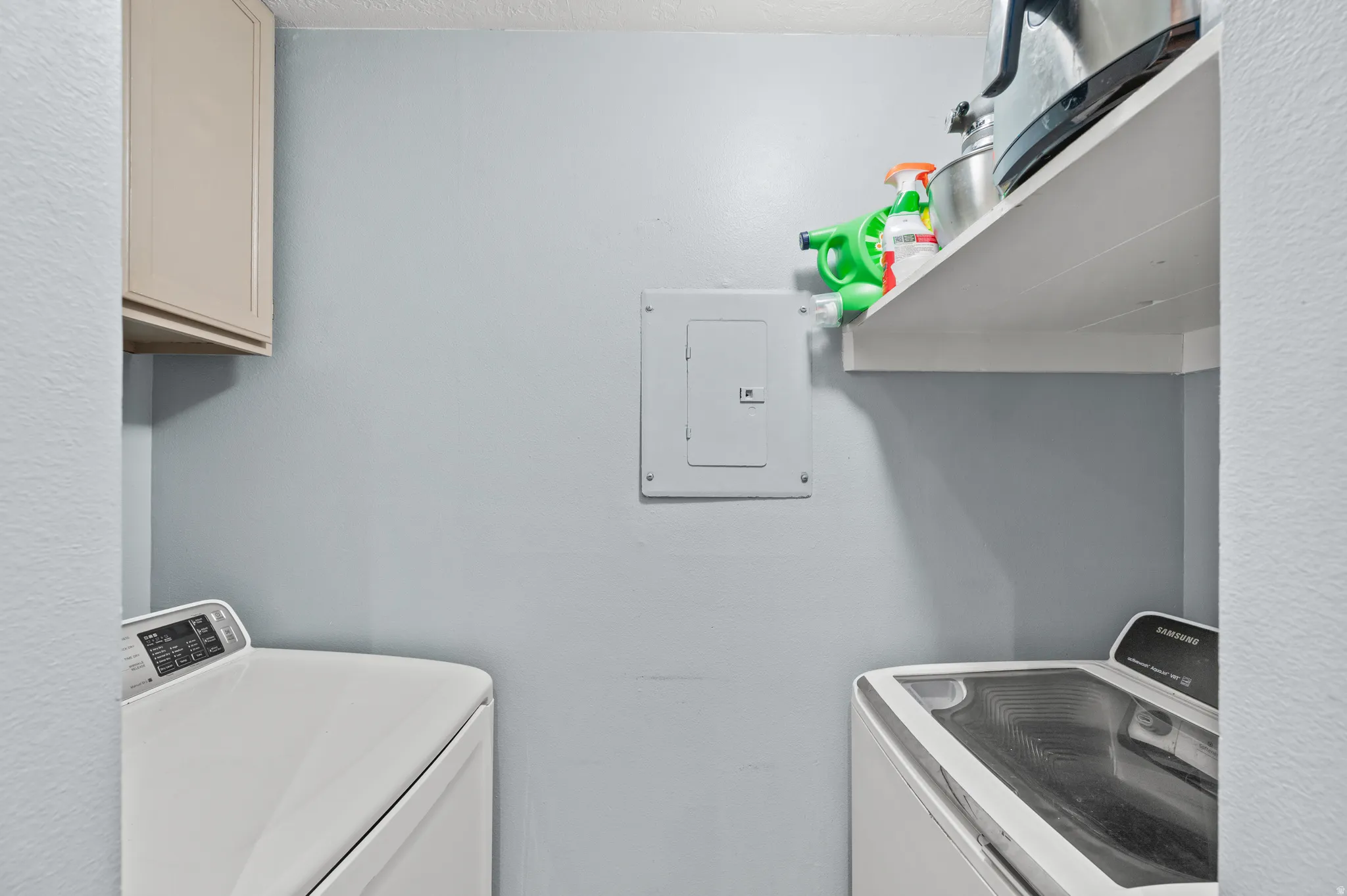 Laundry room featuring washer and clothes dryer, electric panel, and cabinet space