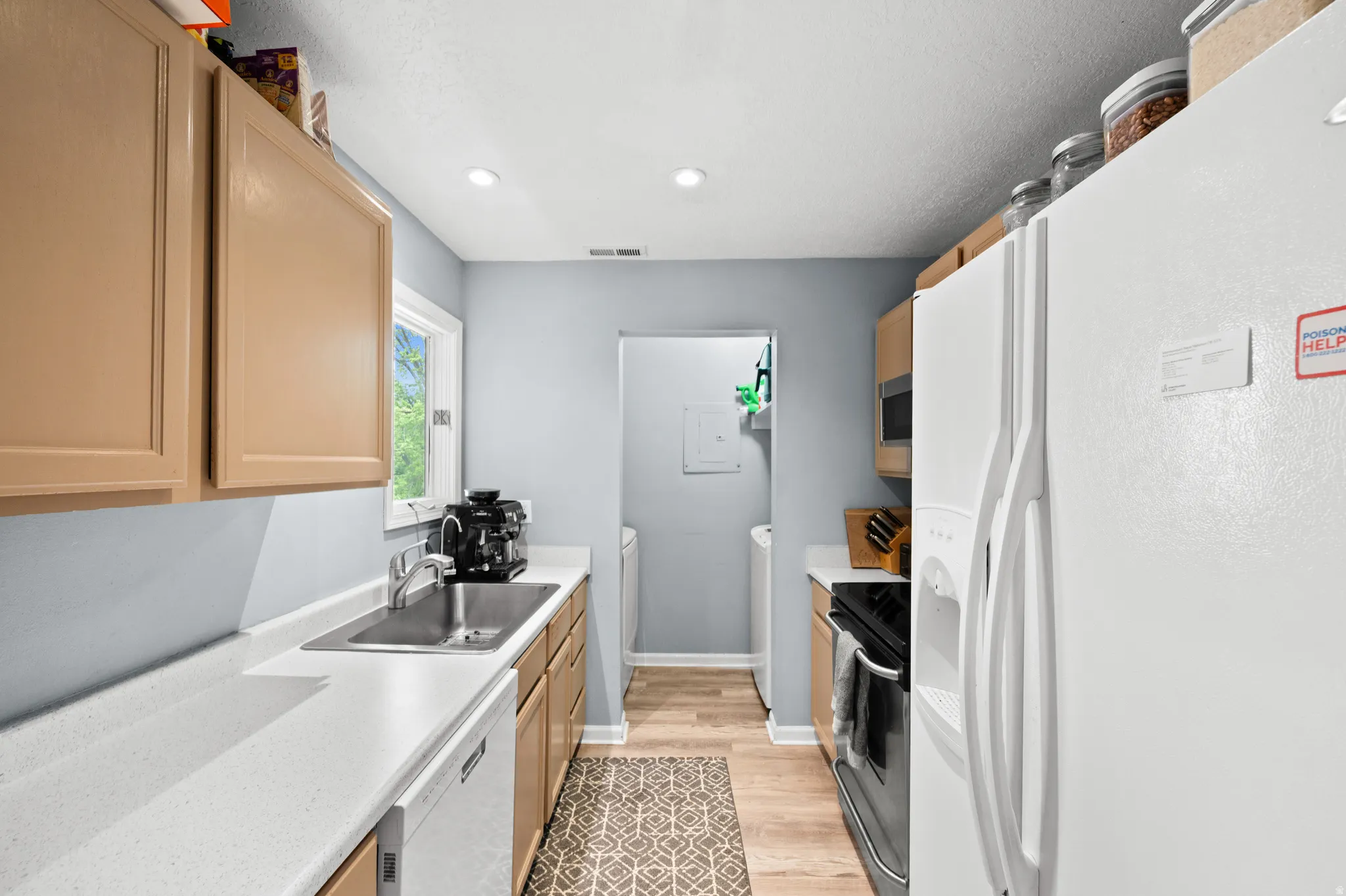 Kitchen featuring white appliances, light wood-type flooring, light wood finish cabinets, and recessed lighting