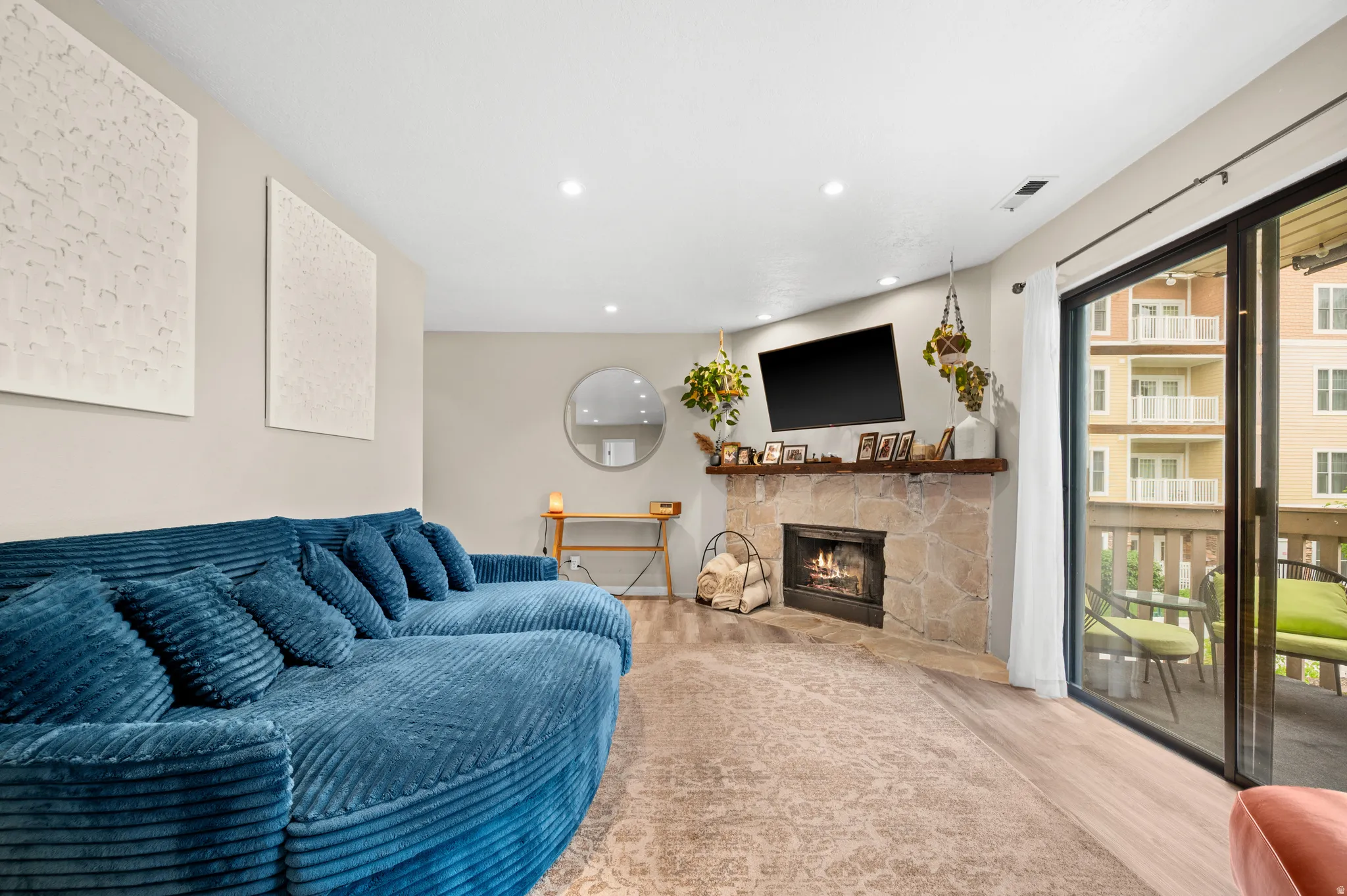 Living room with vinyl floors, recessed lighting, and a stone fireplace.
