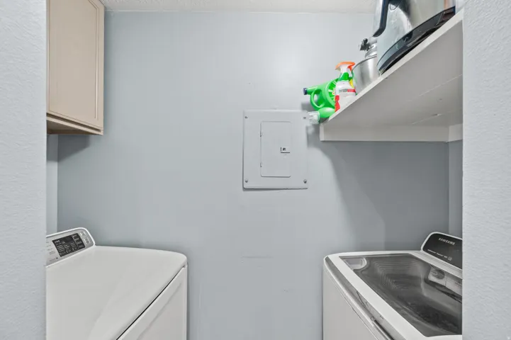 Laundry room featuring washer and clothes dryer, electric panel, and cabinet space