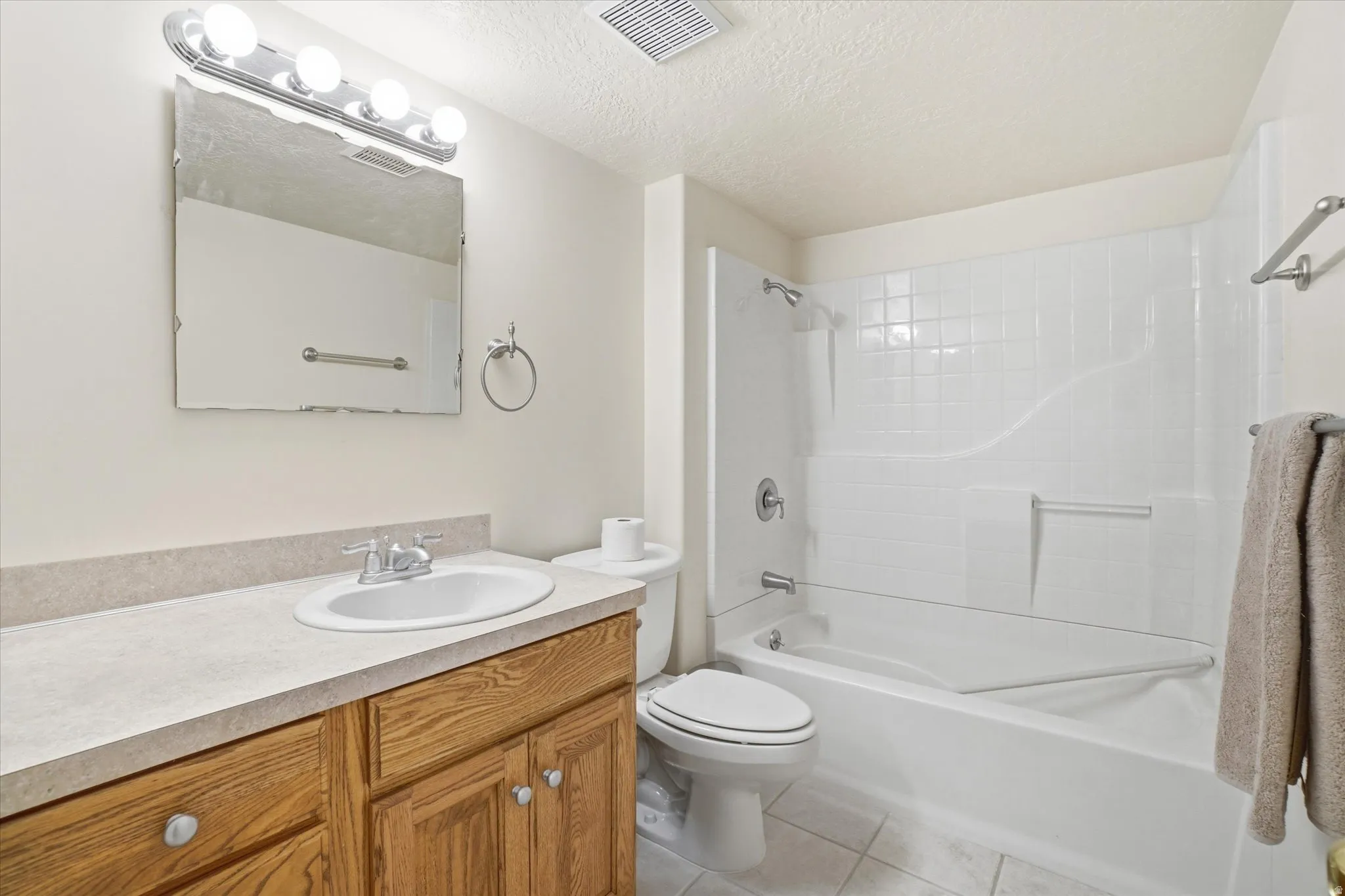 Bathroom featuring a vanity with wood-finish cabinetry, a single basin sink, and a light-colored countertop