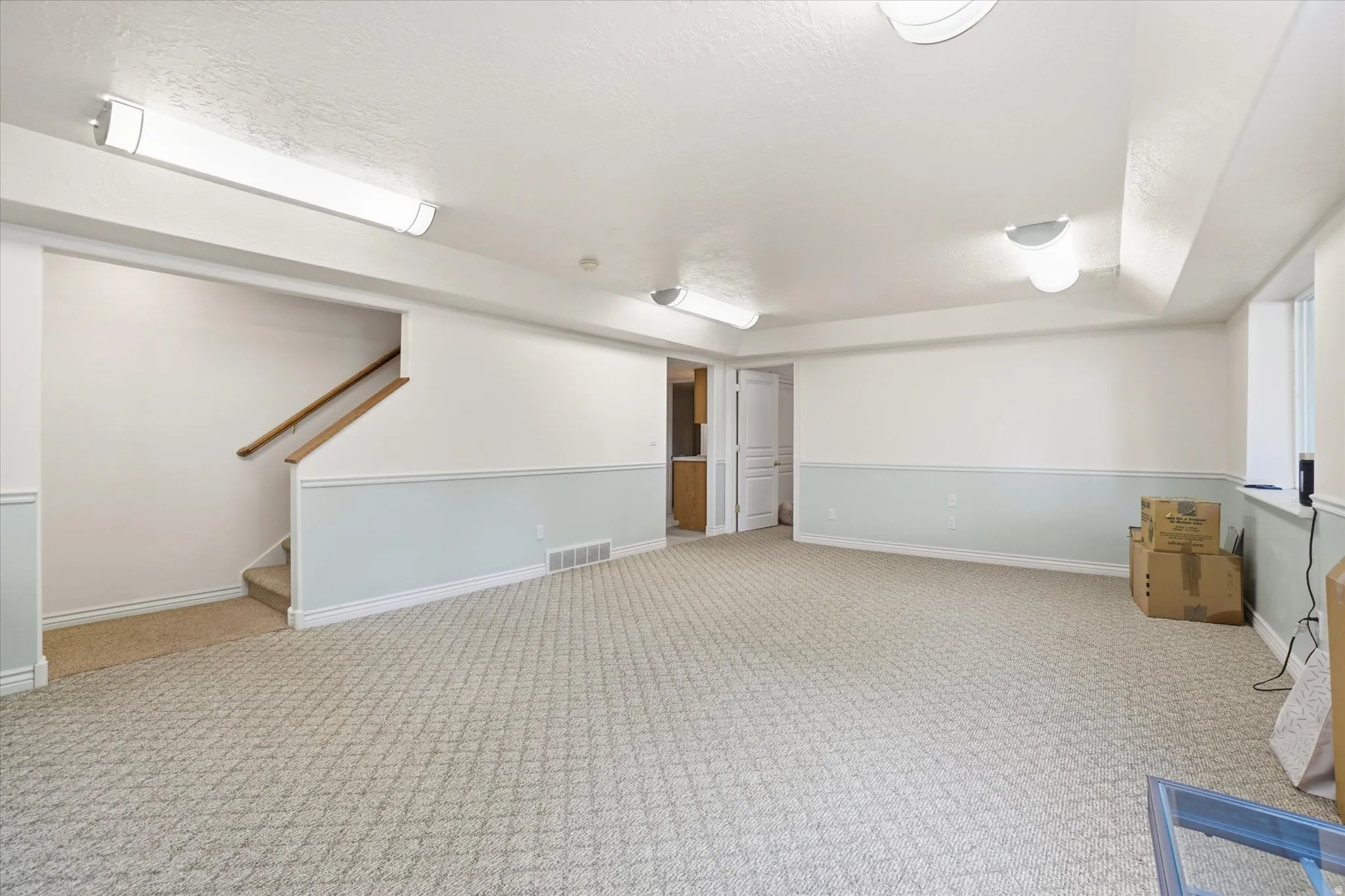 Expansive room featuring patterned carpeting, two-tone wall treatment, and recessed lighting