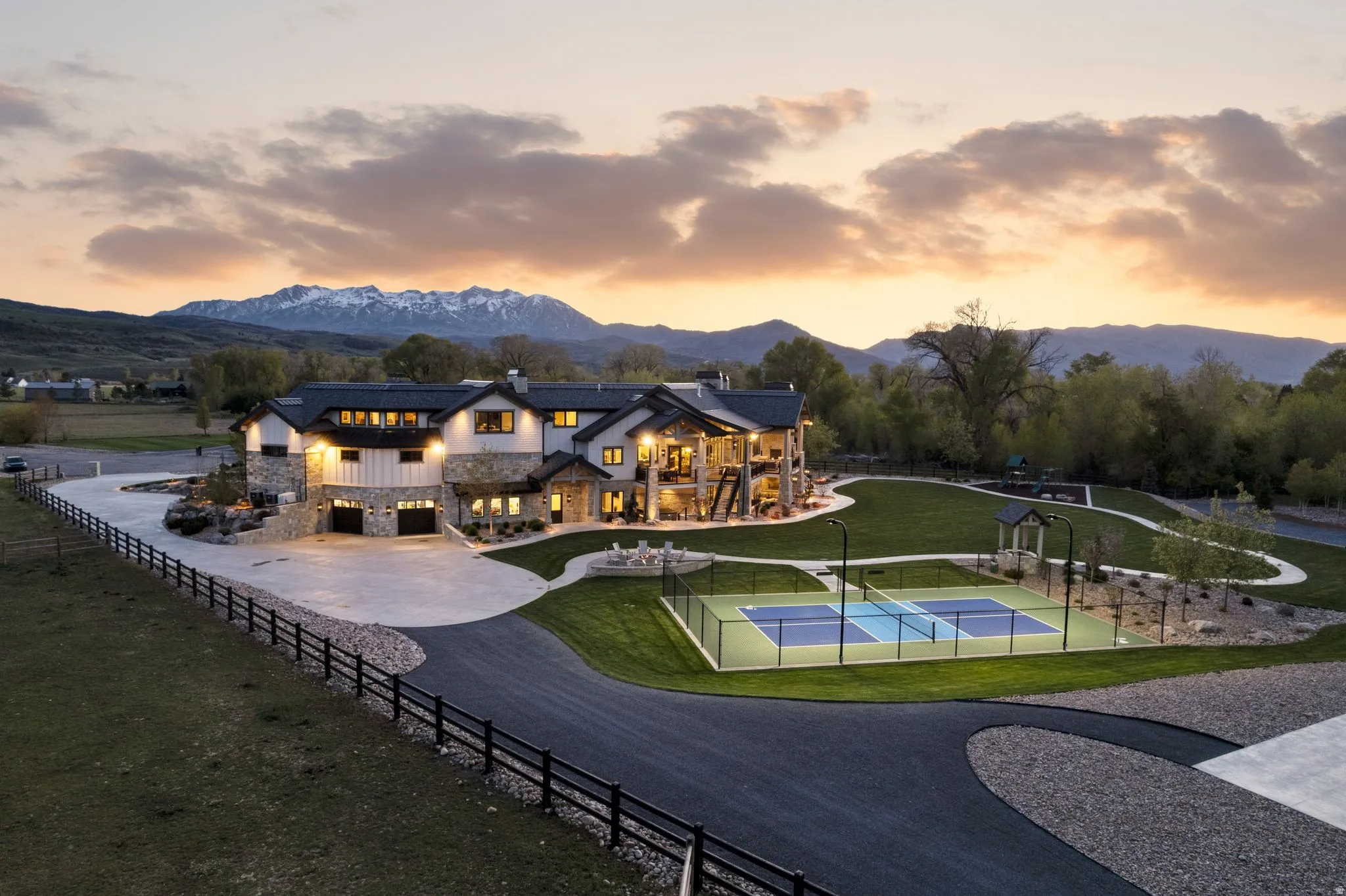 Back of house featuring stone siding, a tennis court, a chimney, and a mountain view