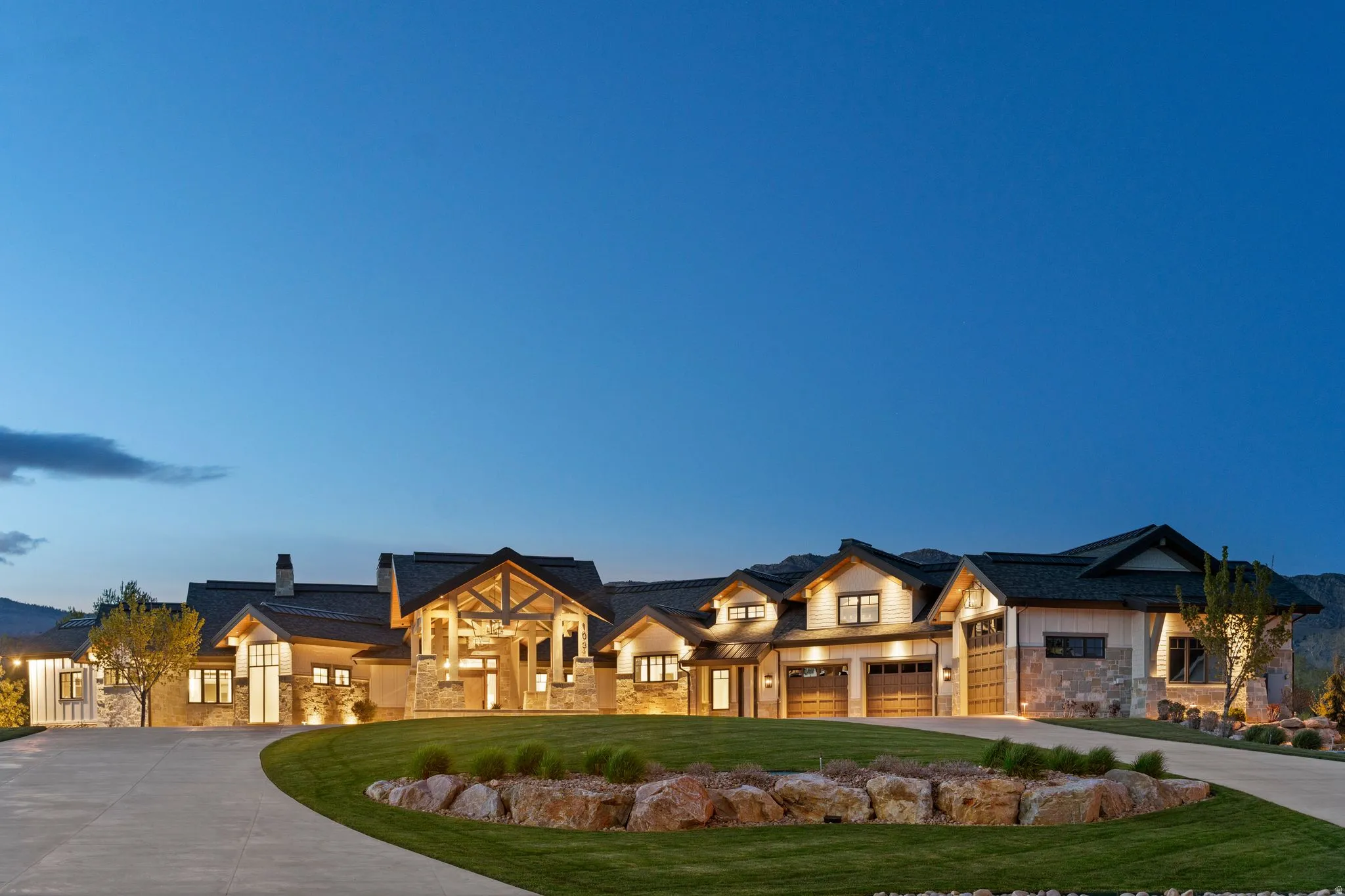 Modern farmhouse style home with stone siding, concrete driveway, a yard, a chimney, and a porch