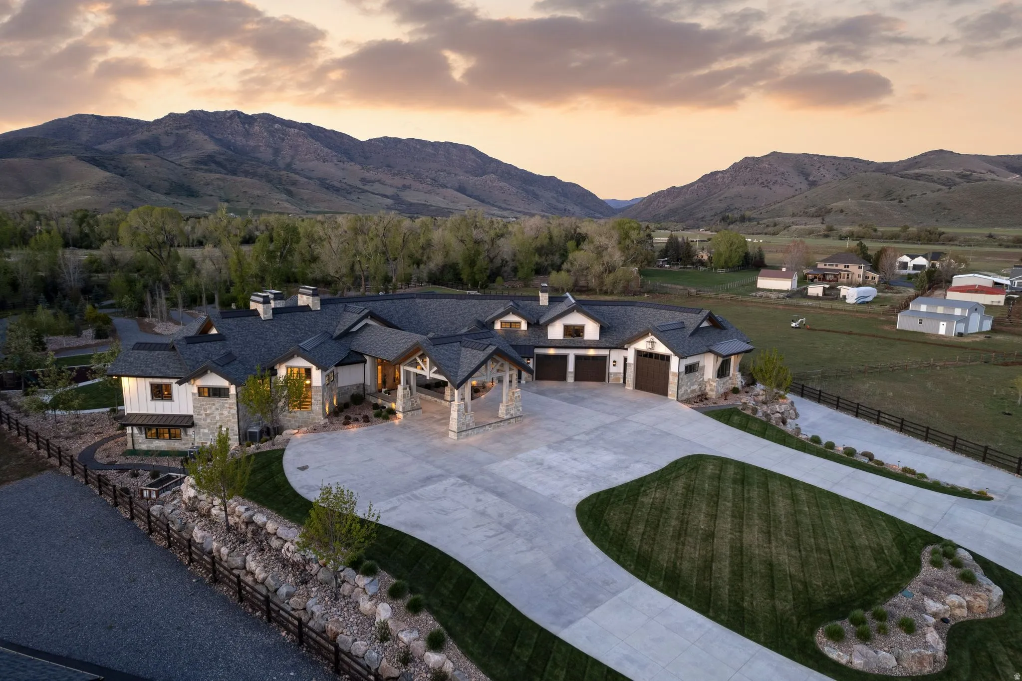 View of front of home with stone siding, a chimney, curved driveway, a garage, and a mountain view