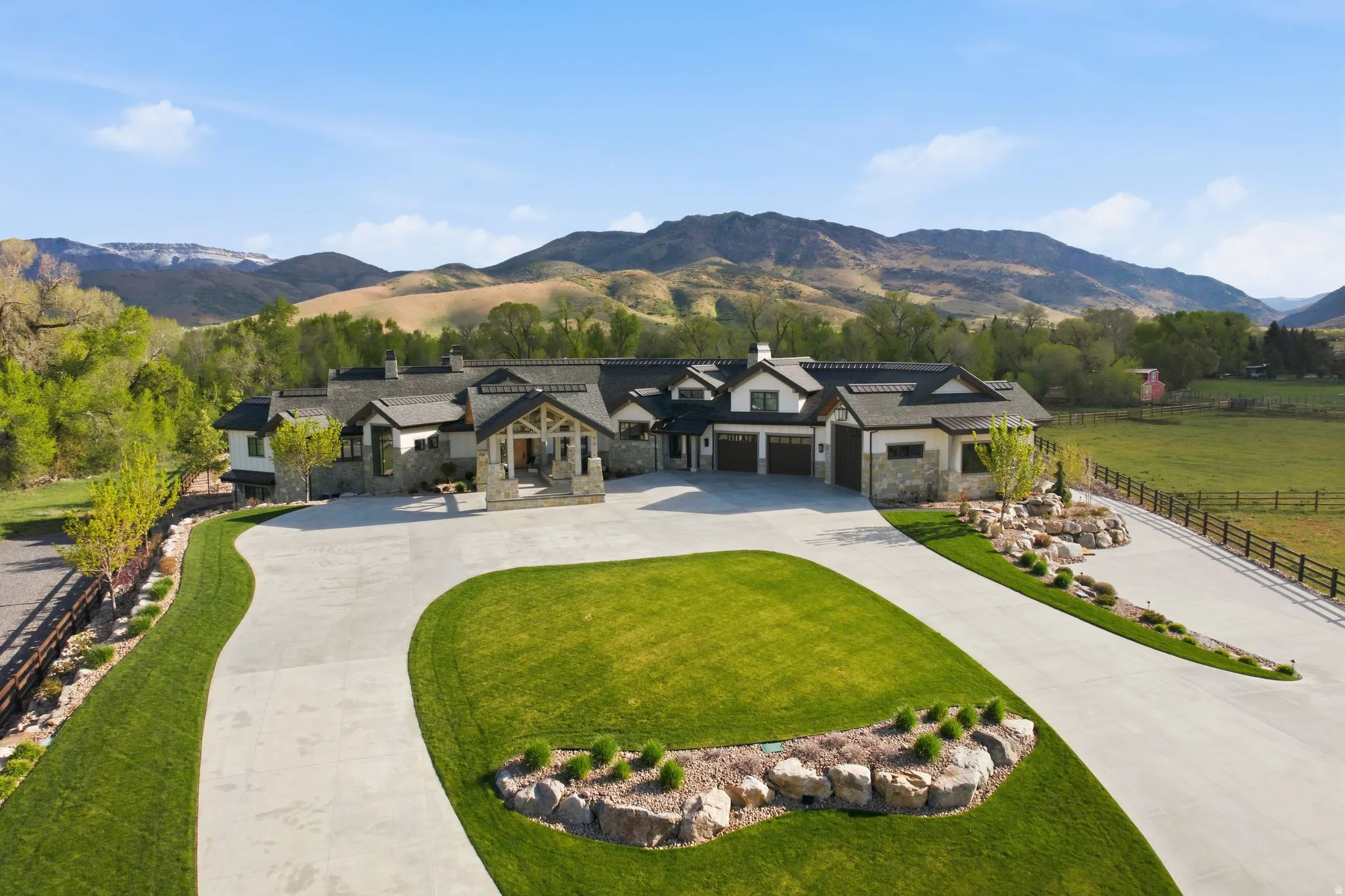 View of front facade with stone siding, a chimney, a mountain view, and curved driveway