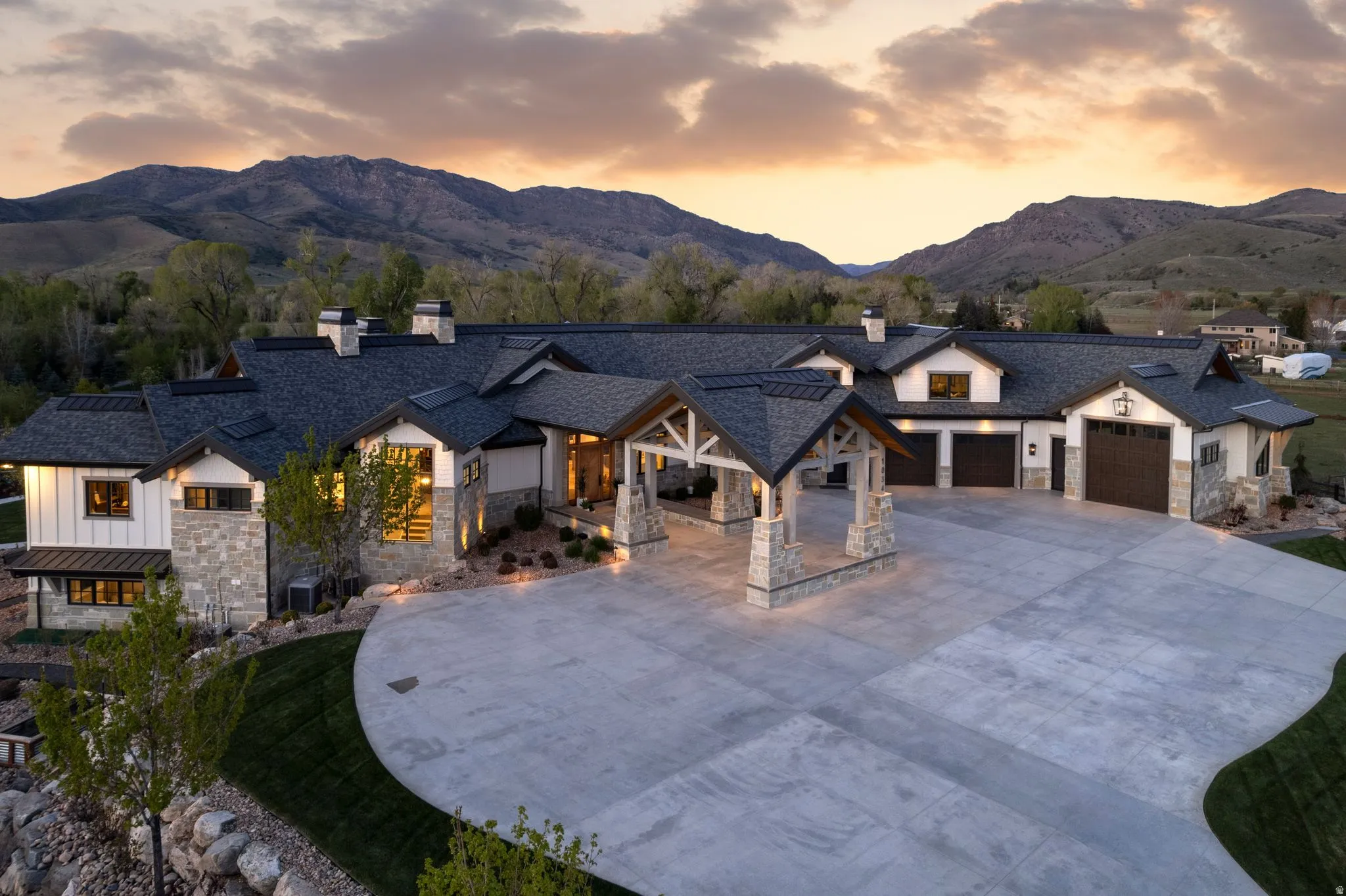 Modern farmhouse style home with a chimney, stone siding, concrete driveway, and a garage
