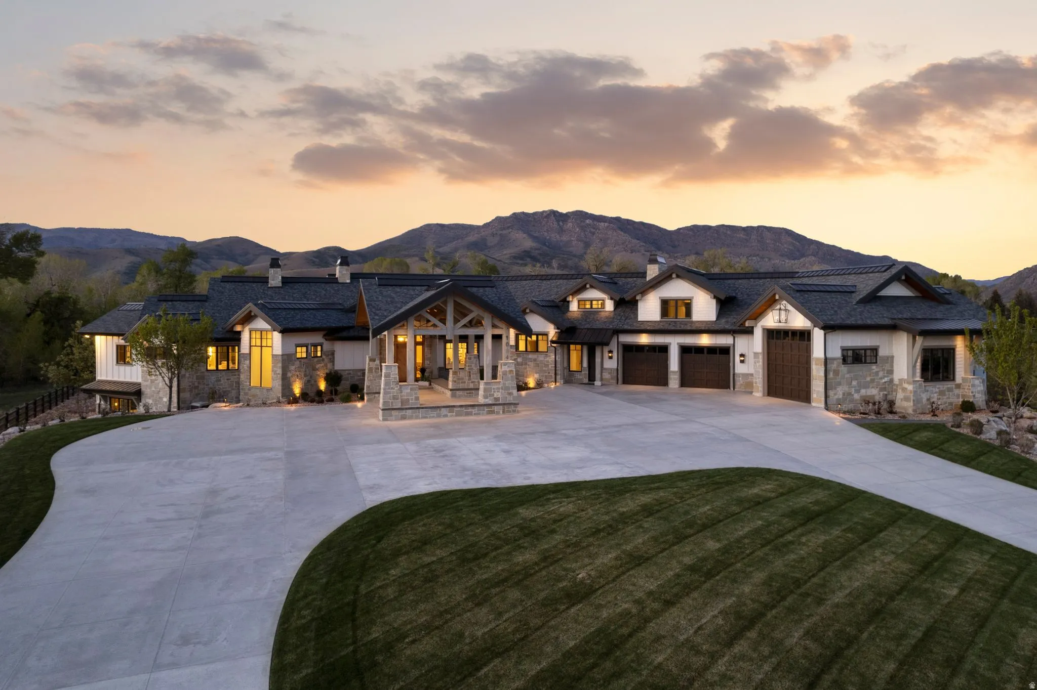 Modern inspired farmhouse featuring a chimney, stone siding, driveway, a mountain view, and a front lawn