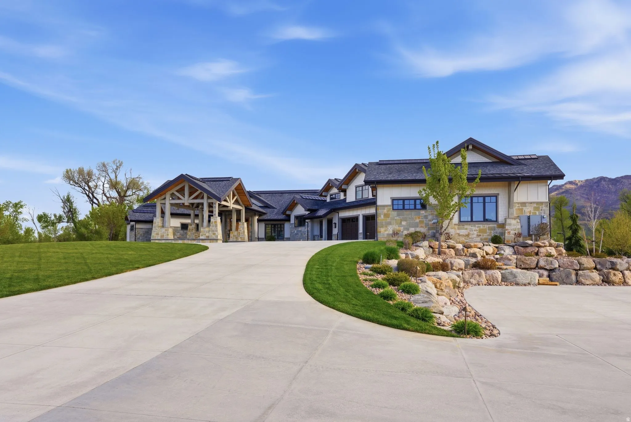 View of front of home featuring stone siding, concrete driveway, and a front yard