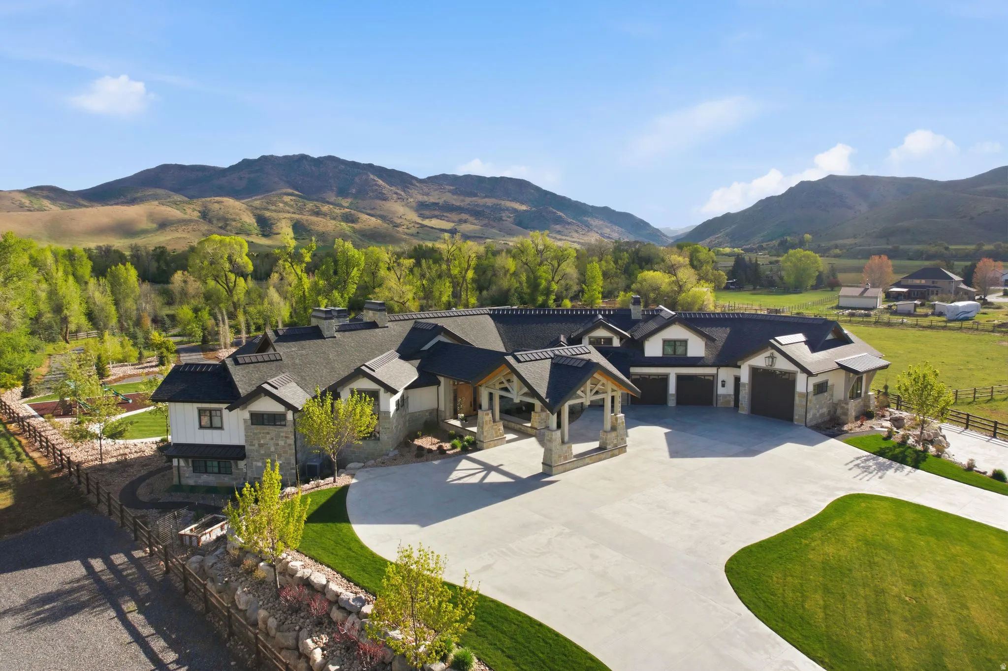 Modern inspired farmhouse with stone siding, a mountain view, driveway, and an attached garage