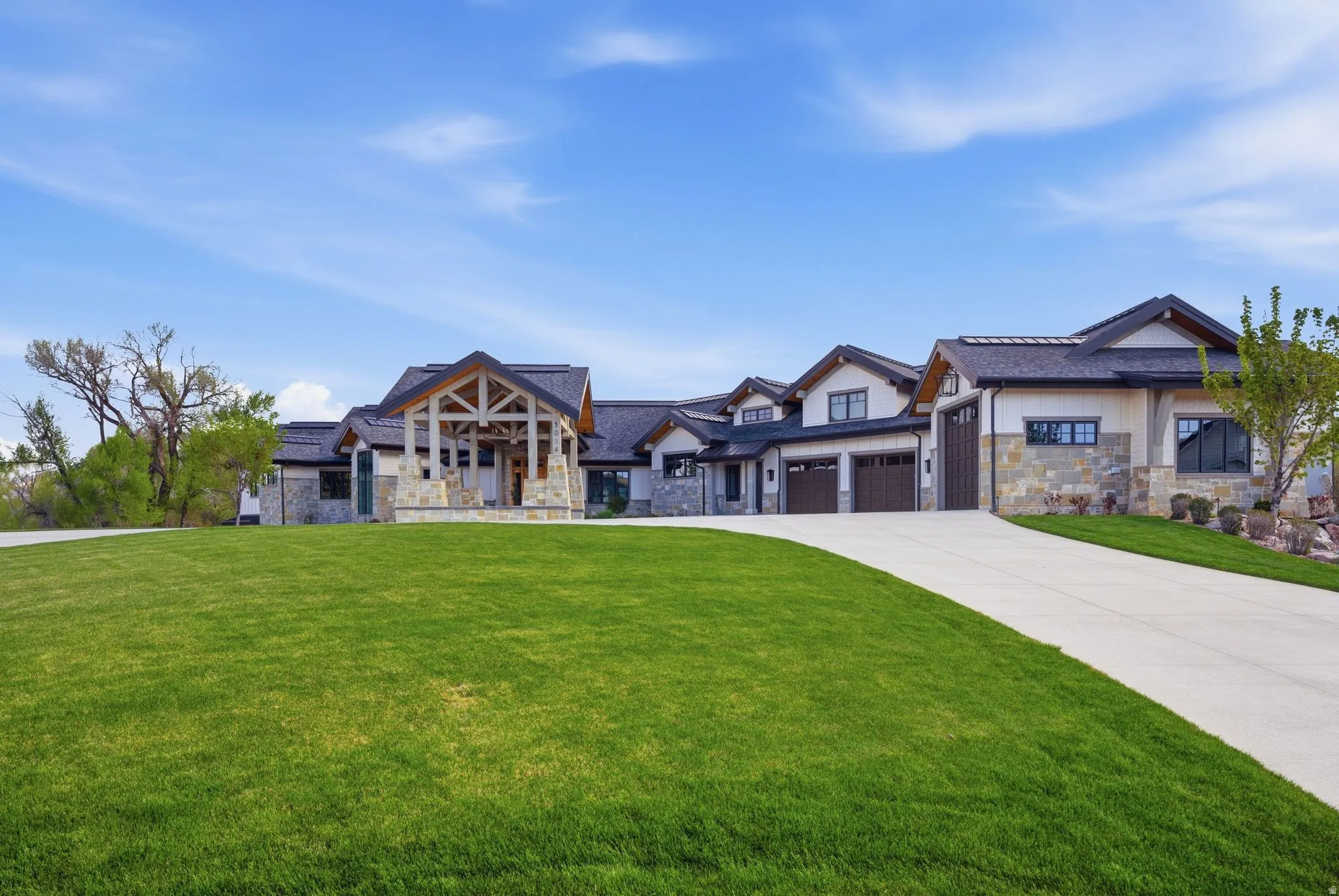 Modern inspired farmhouse featuring stone siding, a front yard, driveway, and a garage