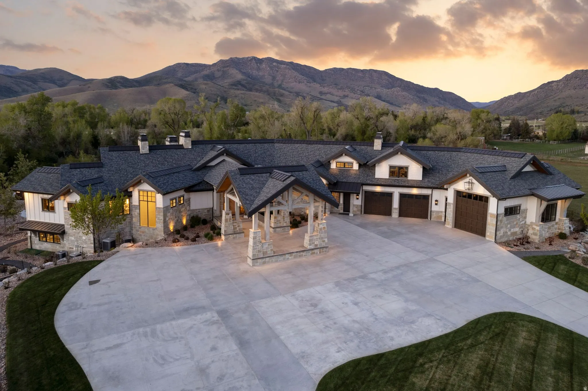 View of front facade with a chimney, a mountain view, concrete driveway, a garage, and stone siding