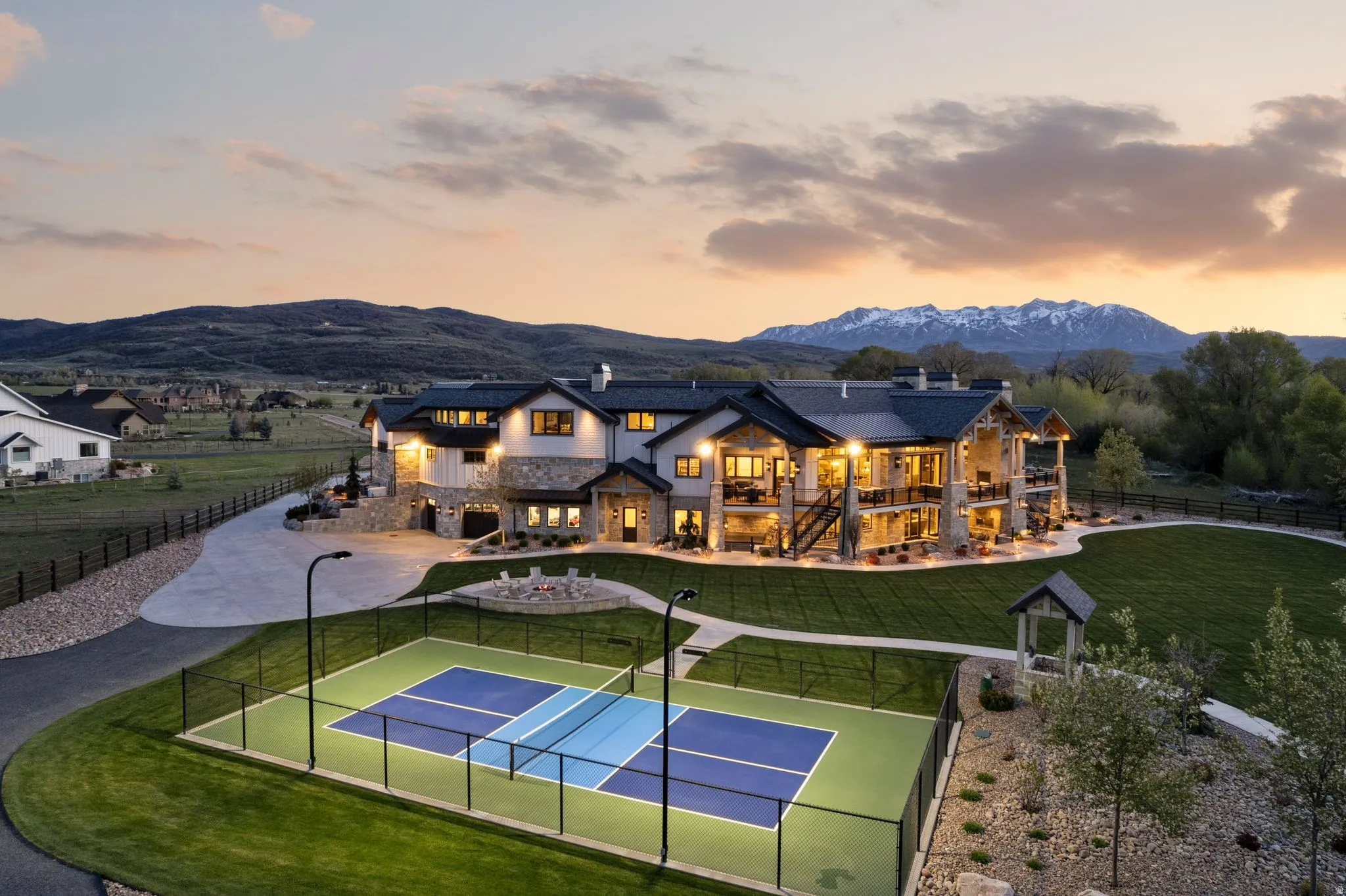 Back of house featuring a chimney, stone siding, a tennis court, and a mountain view